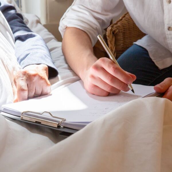 A caregiver's supportive interaction with a senior in a sunlit room, highlighting care and connection.